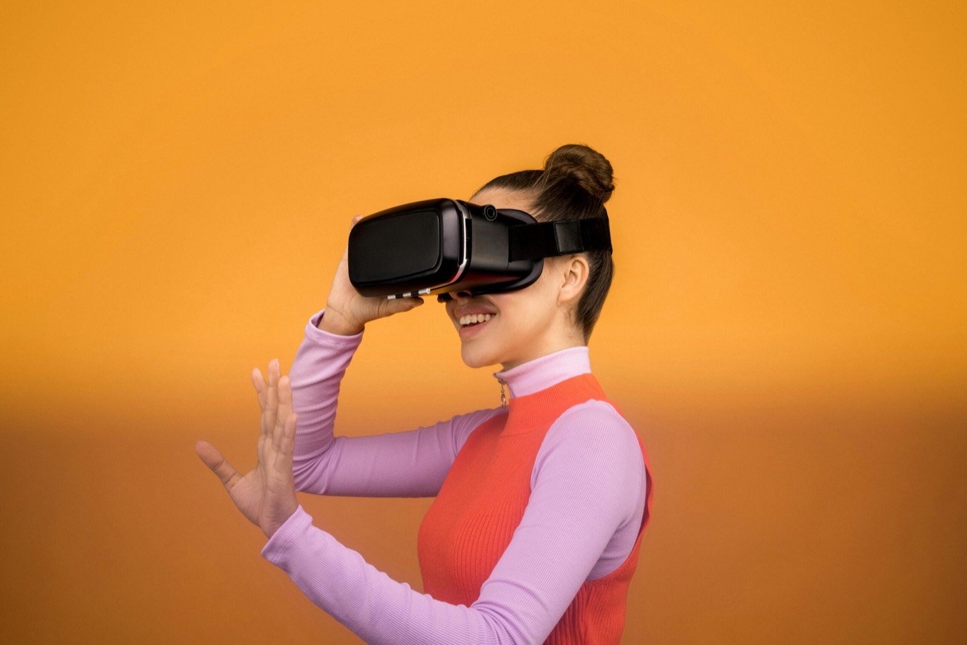 Persoon met VR-bril tegen een oranje achtergrond